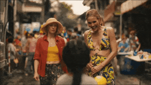 two women are walking down a street in a crowded city .