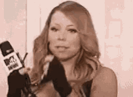 a woman is holding a microphone and wearing gloves while talking into it .
