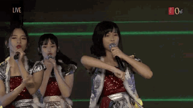 a group of girls are singing into microphones with the words live on the bottom