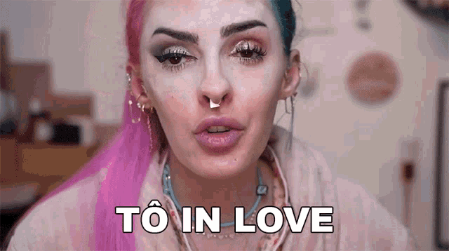 a woman with pink and blue hair is making a funny face and saying to in love .