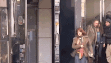a group of people are walking down a sidewalk in front of a building .