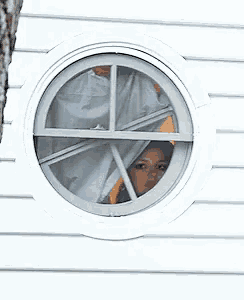 a woman looks out of a round window