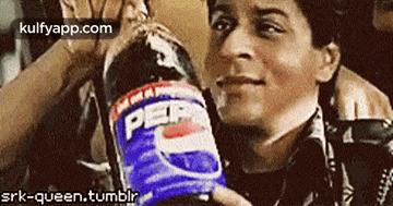 a man is holding a bottle of pepsi and drinking it .