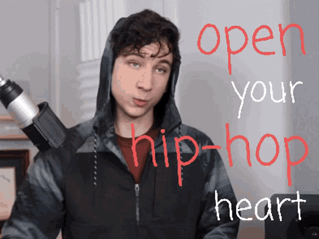 a man in a hooded jacket stands in front of a microphone with the words open your hip-hop heart written in red