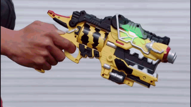 a person is holding a yellow and black toy gun with a red clip in it