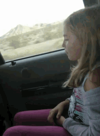 a young girl is sitting in the back seat of a car looking out the window