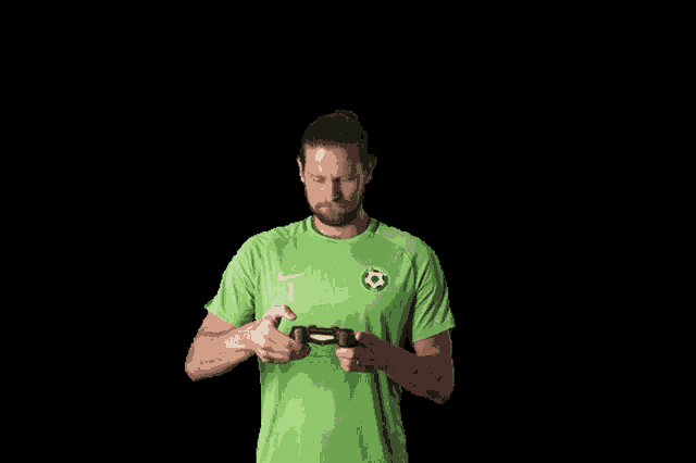 a man in a green shirt with the number 1 on it is playing a video game