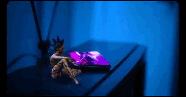 a statue of a man with a mohawk sits on a table next to a cell phone