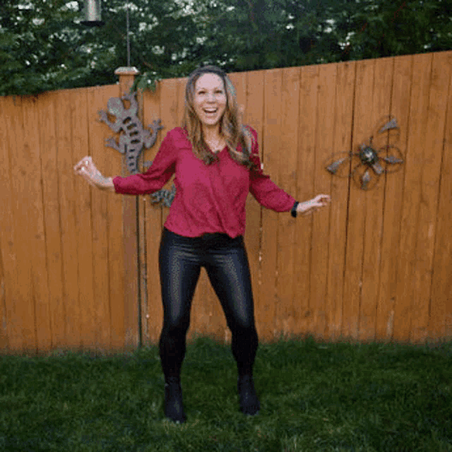a woman standing in front of a wooden fence with a lizard on it