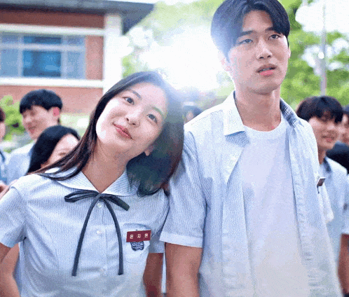 a boy and a girl are standing next to each other in front of a building