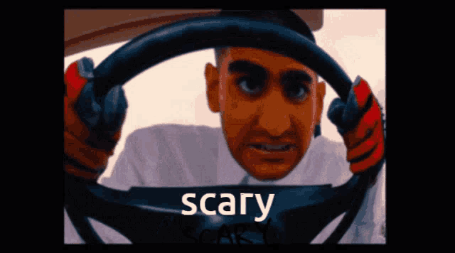 a man is holding a steering wheel and the word scary is on the bottom