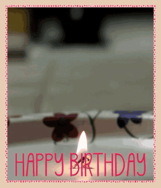 a happy birthday card with a candle and flowers in the background