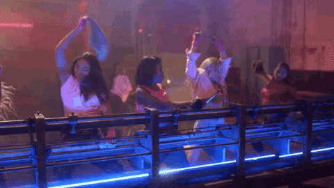a group of people are dancing in a dark room with blue lights .