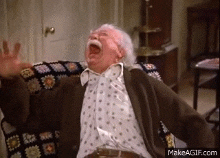 an elderly man with a mustache is sitting in a chair with his arms outstretched .