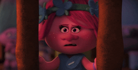 a troll with pink hair and blue flowers in her hair is behind bars