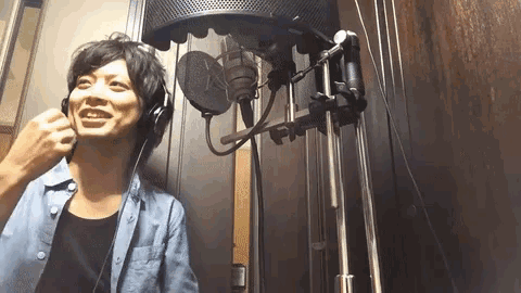 a man wearing headphones is singing into a microphone in a room .
