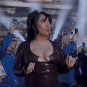 a woman in a black dress is standing in front of a crowd of people