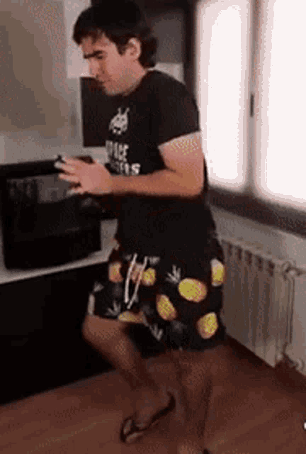 a man in a black shirt and shorts is dancing in a kitchen