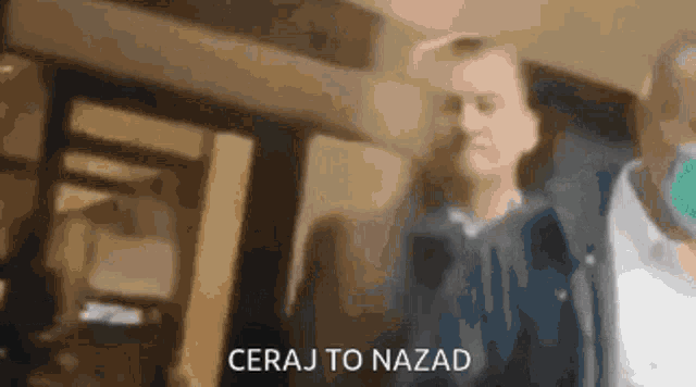a blurry picture of a man standing in front of a building with the words ceraj to nazad written on the bottom .