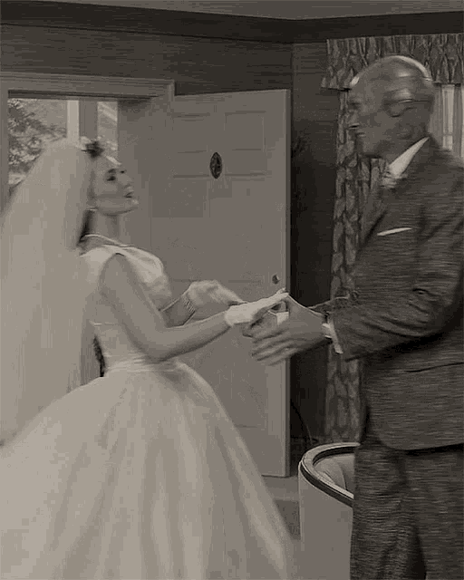 a black and white photo of a bride and groom holding hands .