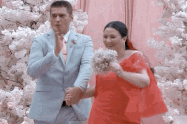 a man in a suit and a woman in a red dress are standing next to each other .