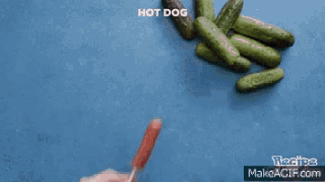 a person is making a hot dog out of cucumbers ..