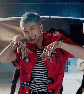 a man with blue hair is wearing a red shirt and a striped shirt and is dancing .