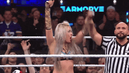 a woman in a wrestling ring with a referee in front of a sign that says earmoorve