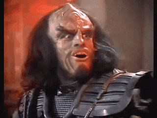 a man with long black hair and a beard is making a funny face .