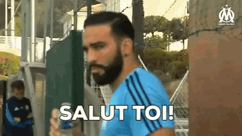 a man with a beard is holding a bottle and says salut toi