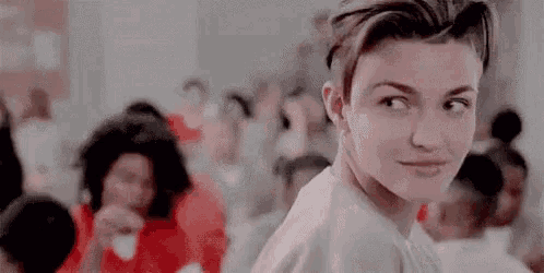 a woman in a white shirt is looking at the camera in a crowded room .