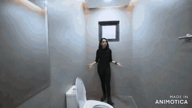 a woman is standing in front of a toilet in a bathroom .