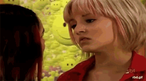 two women are standing next to each other in front of a wall with smiley faces .