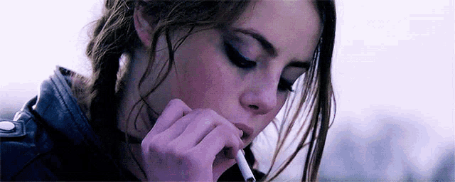 a woman is smoking a cigarette in a close up of her mouth .