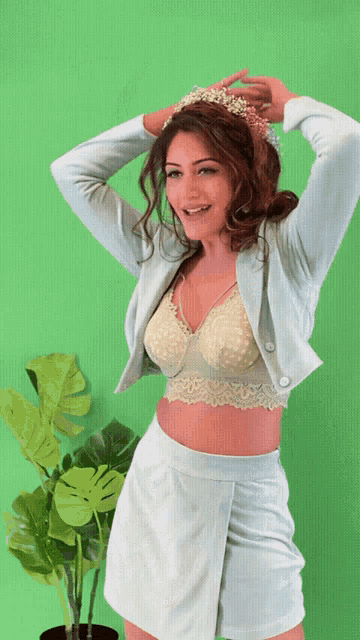a woman wearing a bra and a skirt is standing in front of a green wall
