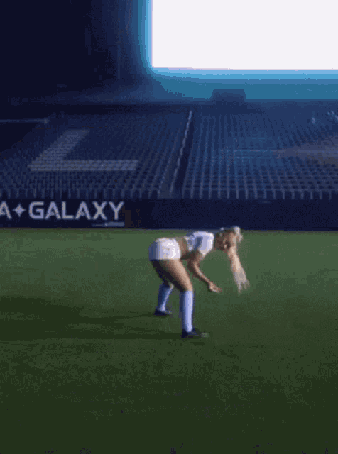a woman on a soccer field in front of a galaxy sign