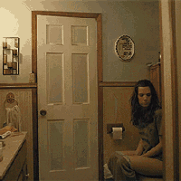 a woman sits on a toilet in a bathroom next to a mirror