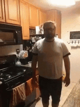 a man in a white shirt is standing in a kitchen next to a stove