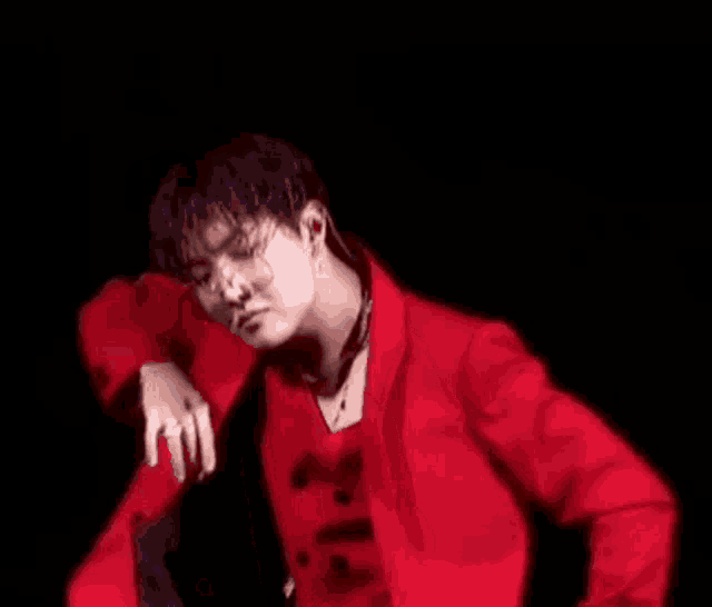 a man in a red suit is dancing on a stage in front of a black background .