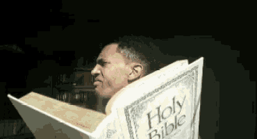 a man is holding a holy bible in front of his head