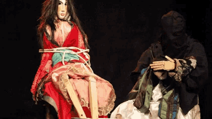 a woman in a red dress is tied up on a chair