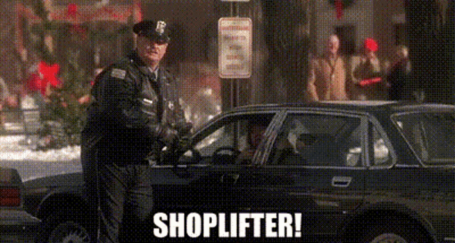 a police officer is standing next to a black car with the words `` shoplifter '' written on it .