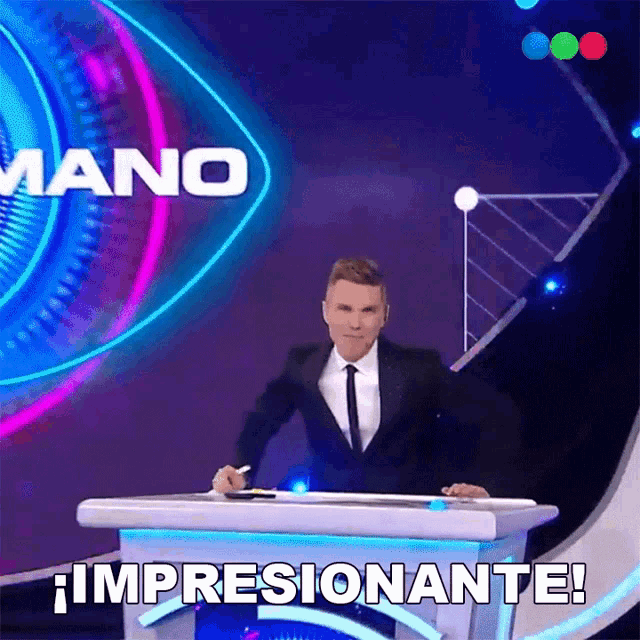 a man in a suit and tie stands behind a podium with the words impresionante written on it