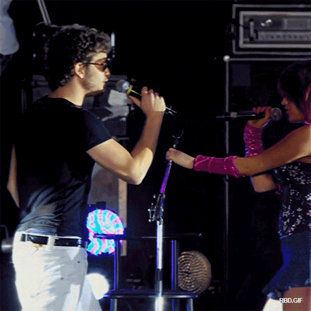 a man singing into a microphone next to a woman with a pink glove