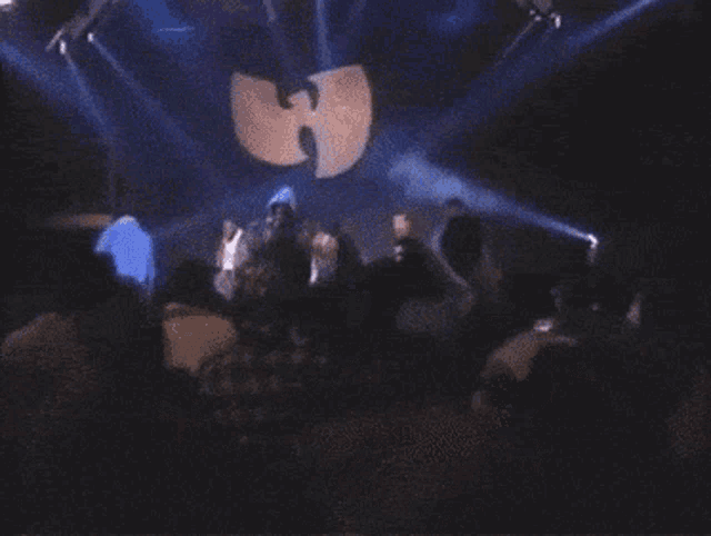 a group of people are standing in front of a stage with a wu-tang logo on it