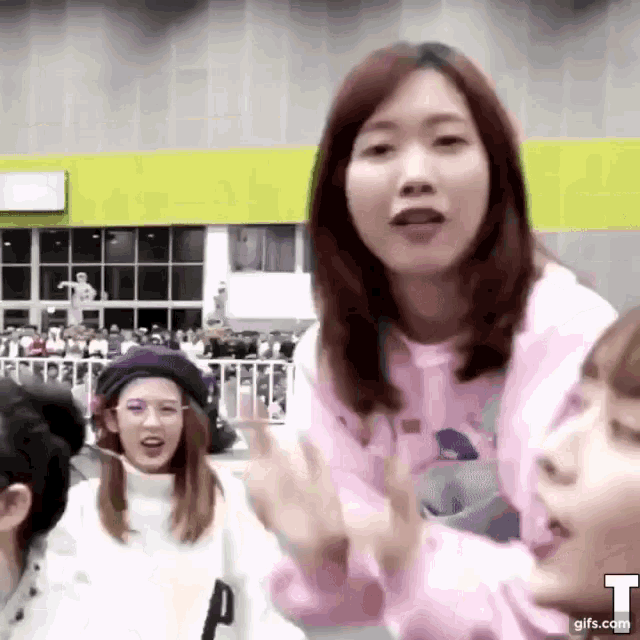 a woman in a pink sweater is talking to another woman in a crowded room .