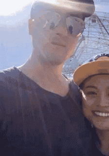 a man wearing sunglasses and a woman wearing a hat are posing for a picture