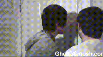 two men are looking at themselves in a mirror with the website ghettosmash.com in the lower right corner