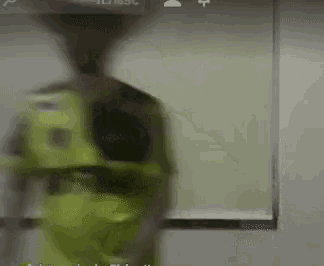 a man wearing a cowboy hat and a green shirt is dancing in front of a whiteboard .