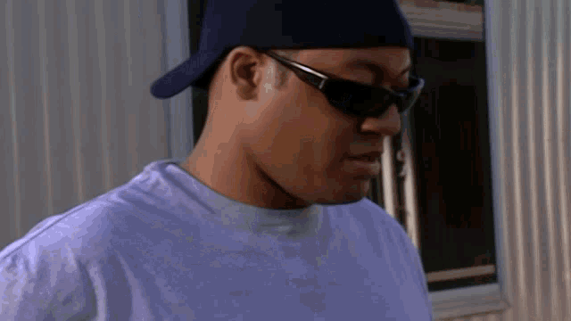 a man wearing sunglasses and a baseball cap looks to the side